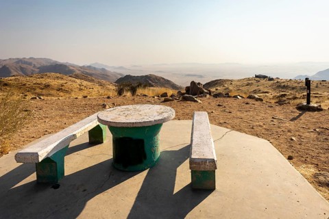 A picnic spot overlooks the vast Namib Desert from Spreetshoogte Pass, with hazy plains, rugged