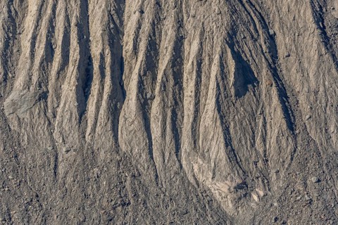 The earth's surface shows clear stripes and reliefs formed by erosion in dry regions. These natural