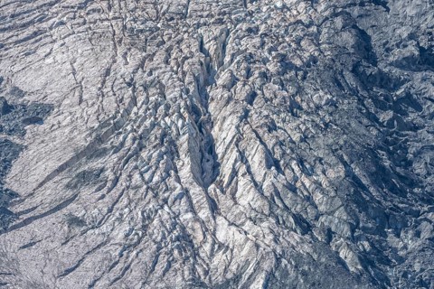 The mountainous landscape reveals impressive glaciers with ice formations and gleaming reflections