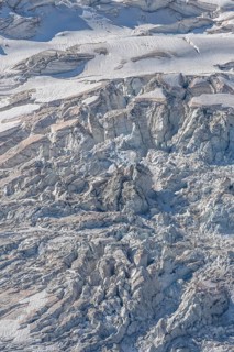 The mountainous landscape reveals impressive glaciers with ice formations and gleaming reflections