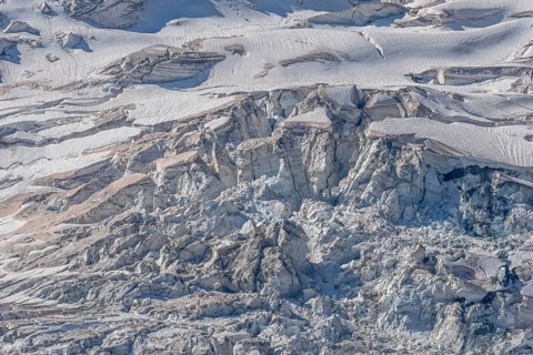A spectacular glacier unfolds in the light, revealing its crevasses and layers of ice in a