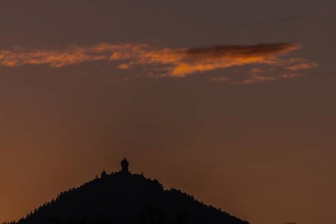 The top of the mountain is cut off against the orange-coloured sky at sunset. The soft light