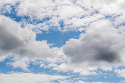 Dense clouds float in the blue sky and create a calming landscape. Natural light illuminates the