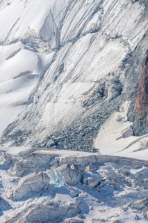 Broad alpine landscape shows glaciers and snow deposits. The mountains are visible in the