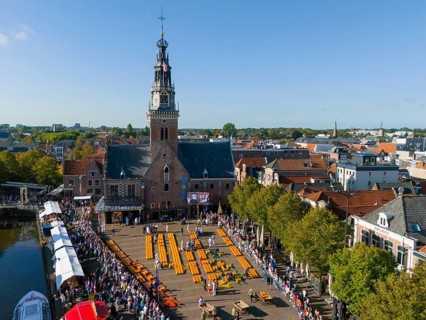 Historic market square with church and crowd under blue sky, aerial view, cheese, cheese market,