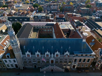 City view of a historic building with striking tower and red tiled roofs, aerial view, town hall,