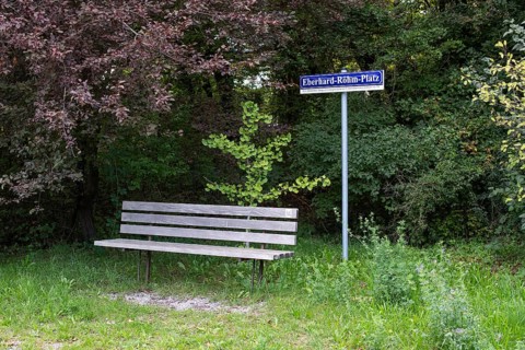 Wooden bench in front of a sign with the inscription Eberhard-Röhm-Platz, square named after a