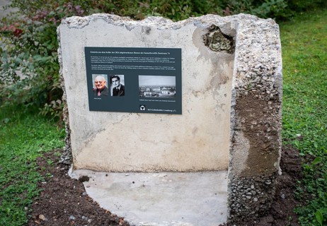 Memorial plaque with photos of a former concentration camp inmate, remains of the walls of a