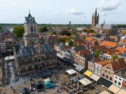 View of the city centre with town hall and lively market square full of people, aerial view, town