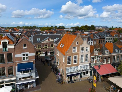 Urban street scene with shops, old buildings and bicycles under a cloudy sky, aerial view, houses
