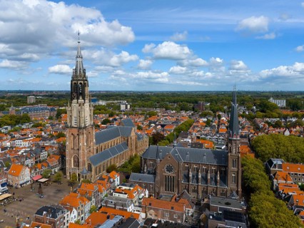 City view with two churches and numerous red roofs under a cloudy sky, aerial view, Nieuwe Kerk,
