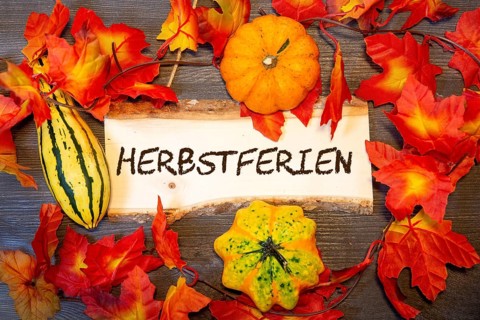 (photomontage) : Wooden sign with the inscription HERBSTFERIEN and autumnal decoration