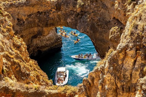 Crowds of excursion boats at the caves and rocky gates of the Ponta da Piedade rocky coast, rugged