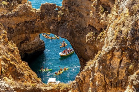 Crowds of excursion boats at the caves and rocky gates of the Ponta da Piedade rocky coast, rugged