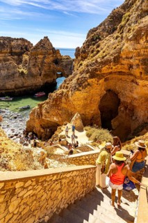 Tourists at the caves and rocky gates of the Ponta da Piedade rocky coast, rugged coastal