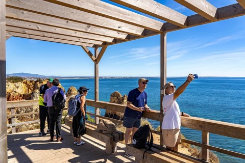 Tourists on the rocky coast of Ponta da Piedade, rugged coastal landscape, right next to Lagos city
