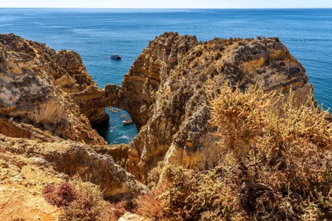 Crowds of excursion boats at the caves and rocky gates of the Ponta da Piedade rocky coast, rugged
