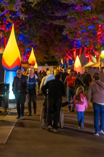 People at a colourful city festival at night with illuminated trees and stalls, Sindelfingen,