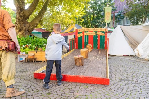 A child plays a medieval wooden game on a market square, Sindelfingen, Böblingen district, Germany