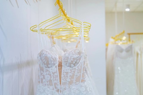 Row of white wedding dresses made of filigree lace presented on yellow hangers, Sindelfingen,