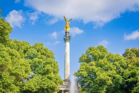 A golden statue rises on a column surrounded by trees, Munich, Germany