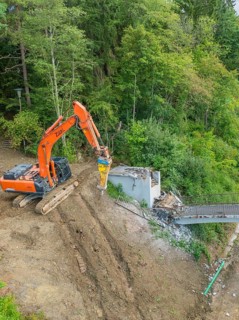 An excavator works on the dismantling of a bridge in a wooded area, bridge demolition, Calw,