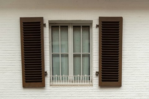 Borken, NRW, Germany, Brown shutters are closed over a window with a white security bar on a white