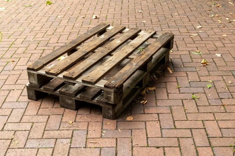 Borken, NRW, Germany, Two weathered wooden pallets are placed on a herringbone brick pavement,