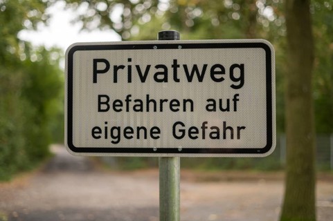 Borken, NRW, Germany, German warning sign privatweg befahren auf eigene gefahr on a pole in a