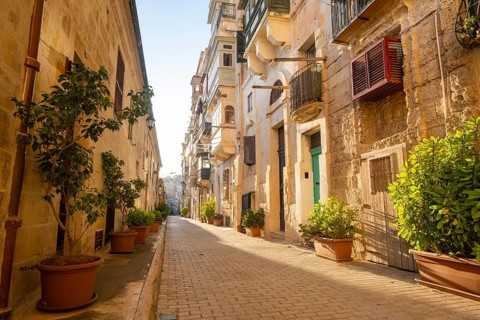 Street with wondeful historic houses with colorful wooden balconies in La Valletta, capital city of
