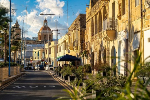 Charming street with limestone building and Saint Mary church at the end, fisherman village of