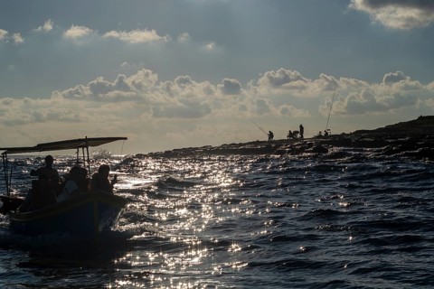 Fishermen on the coast and boat with tourists next to Marsaxlokk, southern part of Malta