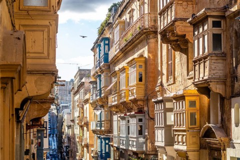 Street with amazing historic houses with colorful wooden balconies in La Valletta, capital city of
