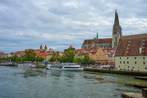 View of a cathedral and boats on a riverbank on a slightly cloudy day, Danube, Regensburg, Bavaria,