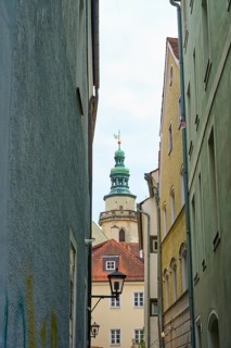 View through a narrow alley to a church tower with surrounding houses, Regensburg, Bavaria, Germany