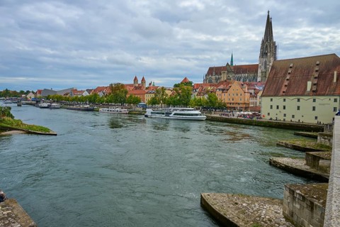 Panorama of a city with cathedral on the riverbank in a cloudy sky, Stone Bridge, Danube,