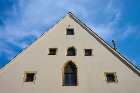 Gable of an old building with Gothic windows in front of a blue sky, Regensburg, Bavaria, Germany