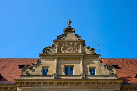 Baroque building front with sculptures and decorative stone ornaments under a clear sky, district