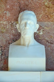 Marble bust of Moltke against a red background, classical style with a serious expression,