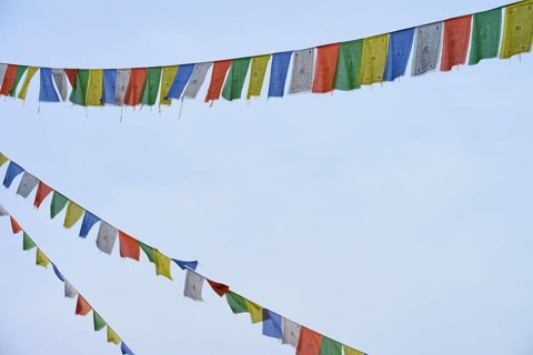 Colourful prayer flags waving gently against the blue sky and creating a meditative atmosphere,