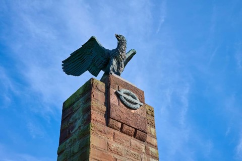 Close-up of an eagle on a stone monument in front of a clear blue sky. Radiance of majesty and