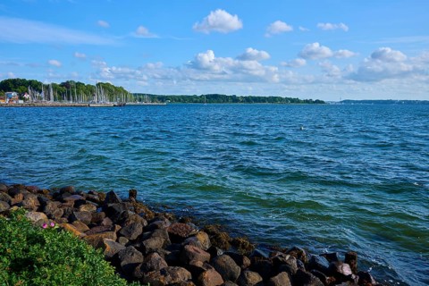 Coastal scene with rocky shoreline and blue sky dotted with clouds, Heikendorf, Plön district, Kiel