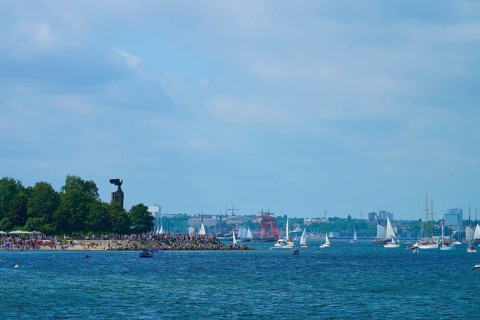 Boats and yacht on the sea near a tree-covered shore with people, Windjammer Parade Kiel 2025,