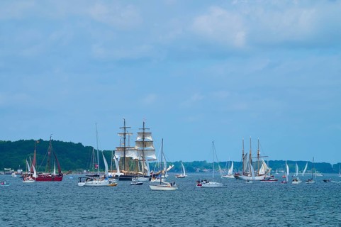 Numerous yachts and sailing ships sailing under a slightly cloudy sky, Windjammer Parade Kiel 2025,
