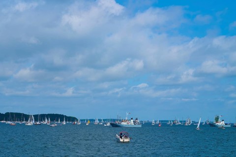 Scattered boats on the sea under a cloudy blue sky, wide visible, Windjammer Parade Kiel 2025,