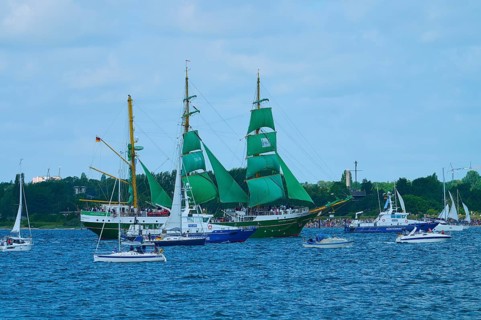 A large sailing ship with green sails Alexander von Humbold 2 and other boats on blue water,