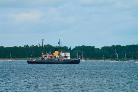 Icebreaker Stettin on a calm sea with several sailing boats and a cloudy sky, Windjammer Parade
