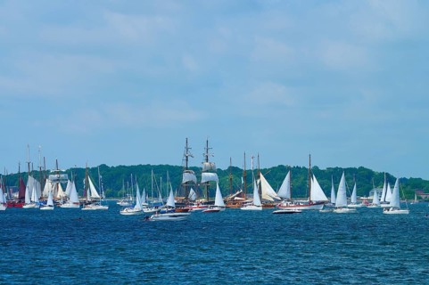 Many sailing boats and a large sailing ship on the sea under a blue sky with clouds, Windjammer