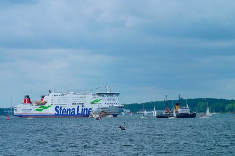 Stena Line ferry and historic ship in a sea travelled by sailing boats with cloudy sky, Windjammer