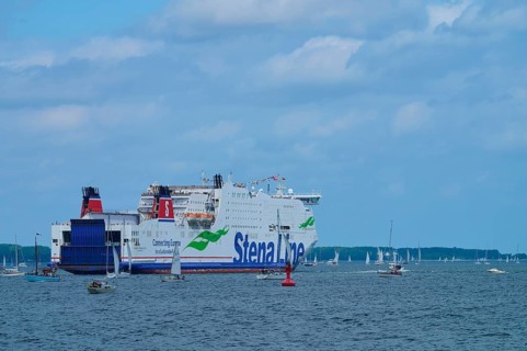 Large ferry on the sea surrounded by sailing boats under a slightly cloudy sky, Windjammer Parade